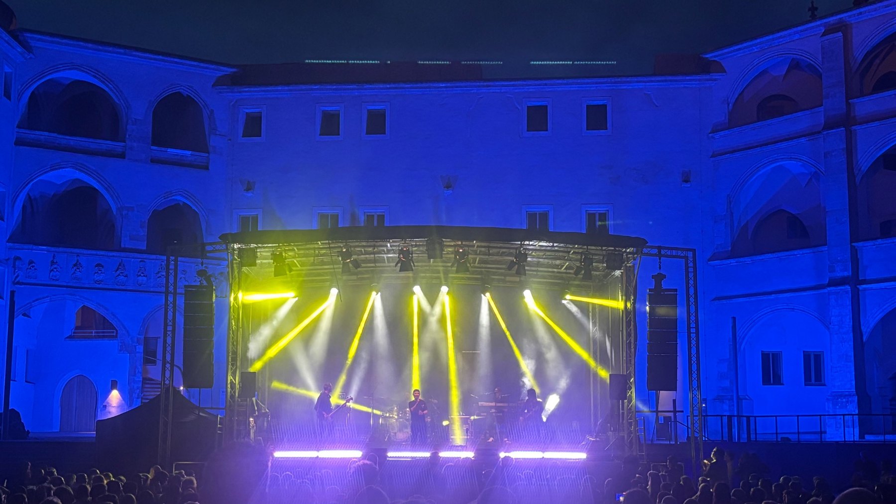Konzertbühne mit gelben Lichtstrahlen und blauer Architekturbeleuchtung
